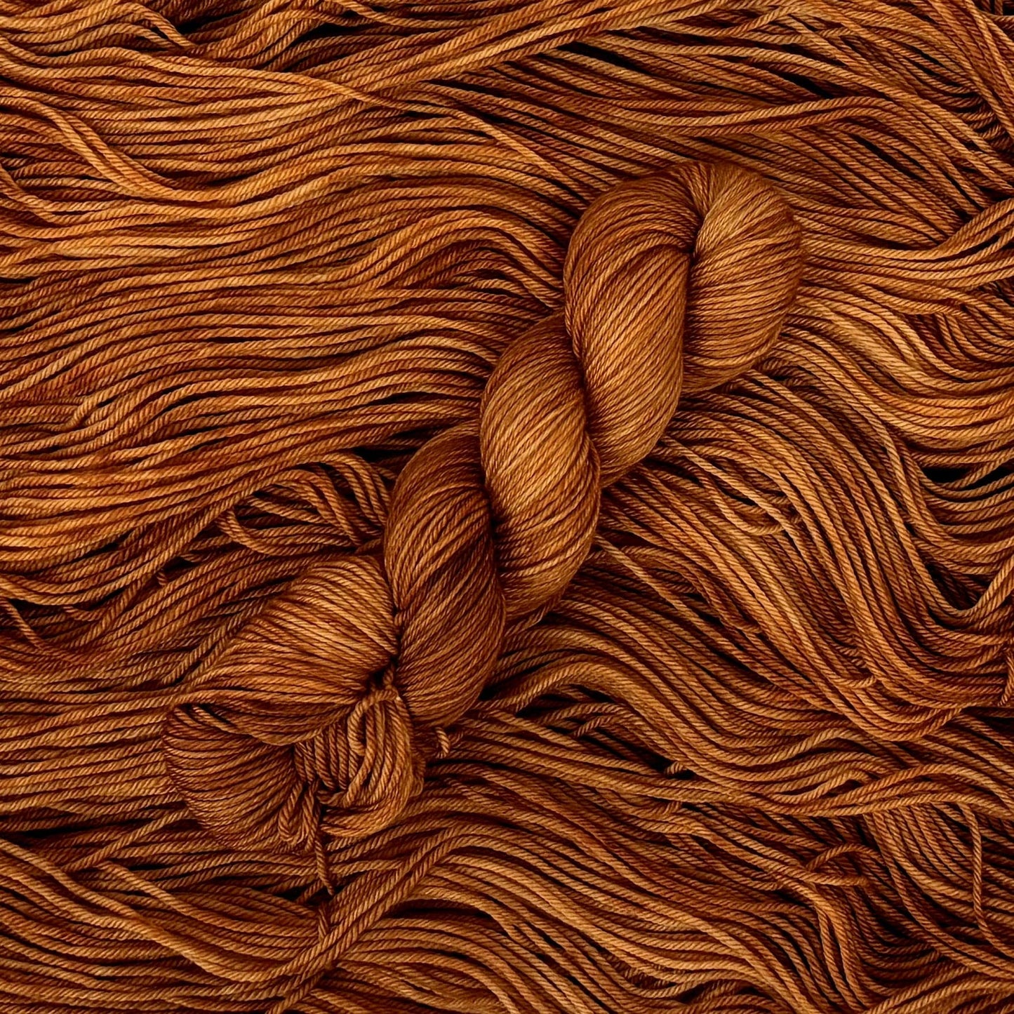 Close-up of brown yarn with a skein on a textured brown background