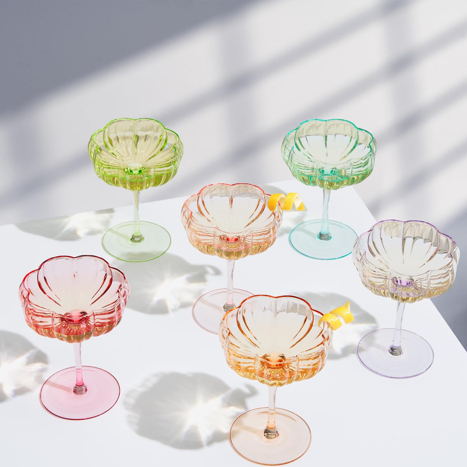 Set of colorful glass cocktail glasses on a white surface with a soft shadow background CMH Goods
